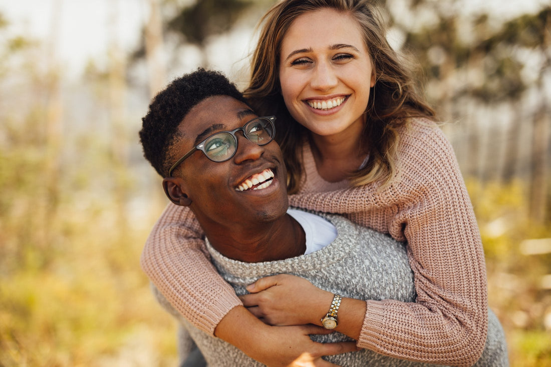 A couple laughing together outdoors during a piggyback moment