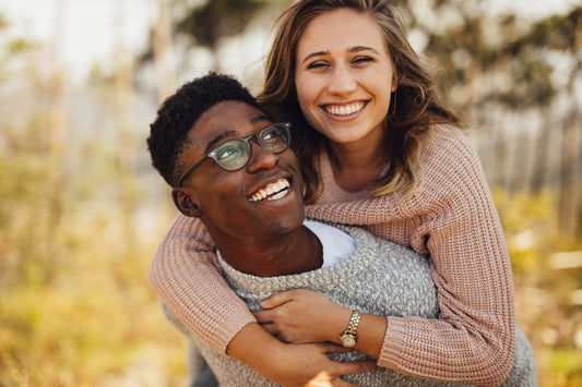 A couple laughing together outdoors during a piggyback moment
