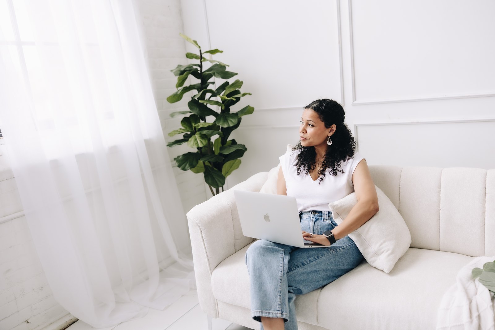 Ashley Harmon seated on a sofa with a laptop during a virtual counseling session